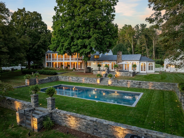 back house at dusk featuring a yard