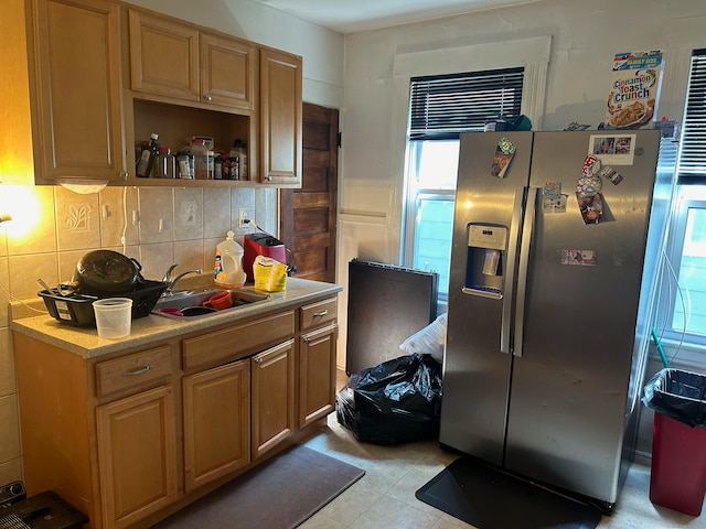 kitchen featuring sink, light tile patterned flooring, stainless steel fridge with ice dispenser, and backsplash