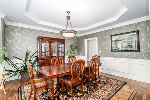 dining area with a tray ceiling, hardwood / wood-style floors, and ornamental molding