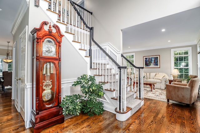 stairs featuring a healthy amount of sunlight, ornamental molding, and hardwood / wood-style flooring