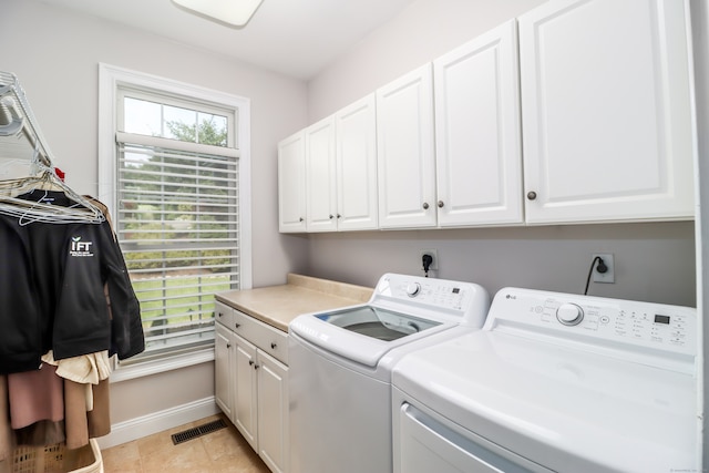 laundry room featuring light tile patterned floors, washer and clothes dryer, and cabinets