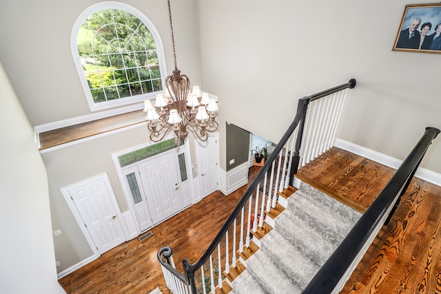 entryway with an inviting chandelier, hardwood / wood-style flooring, and a towering ceiling