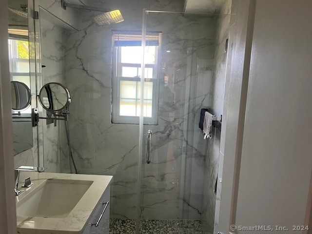 bathroom with a wealth of natural light, an enclosed shower, vanity, and tile walls