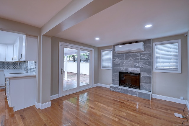 unfurnished living room with a fireplace, light hardwood / wood-style flooring, and an AC wall unit