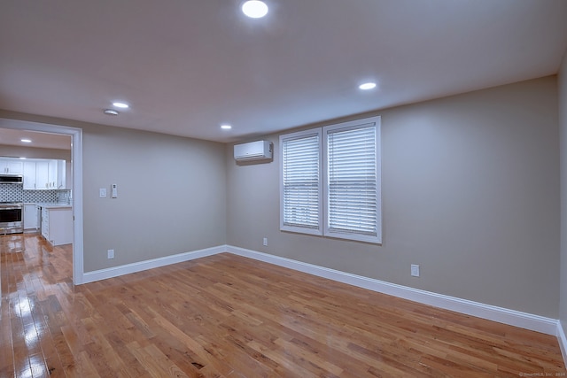 empty room featuring light hardwood / wood-style floors and an AC wall unit