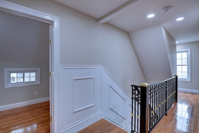 staircase with hardwood / wood-style floors, vaulted ceiling with beams, and plenty of natural light