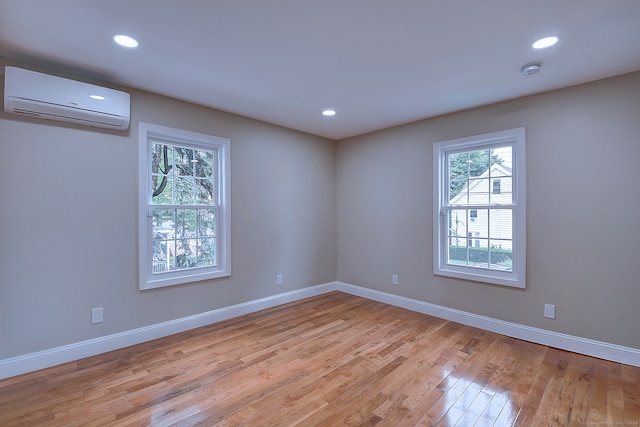 empty room with a wall mounted AC and light hardwood / wood-style floors