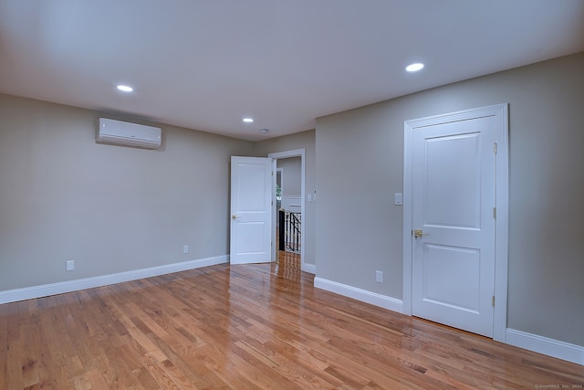 empty room with light hardwood / wood-style floors and an AC wall unit