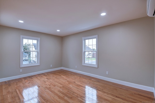 empty room with light hardwood / wood-style floors and a wall mounted air conditioner