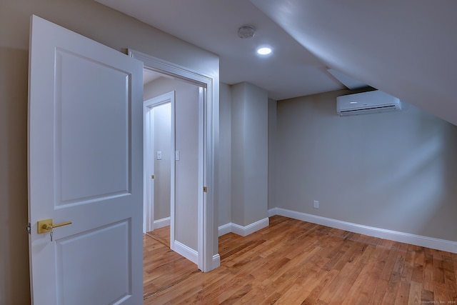 bonus room with a wall unit AC and light hardwood / wood-style floors