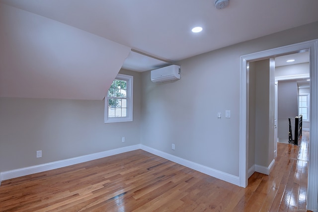 bonus room with light hardwood / wood-style floors, a wall mounted AC, and vaulted ceiling