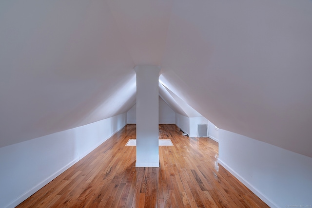 additional living space with light hardwood / wood-style flooring and lofted ceiling