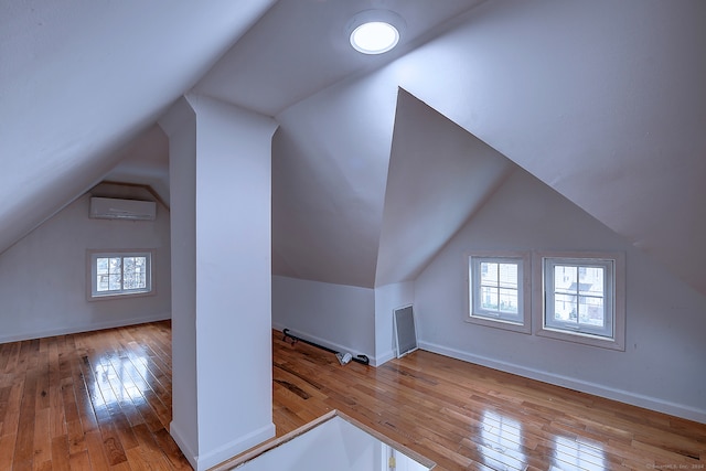 bonus room featuring vaulted ceiling, a wall mounted air conditioner, and light hardwood / wood-style flooring