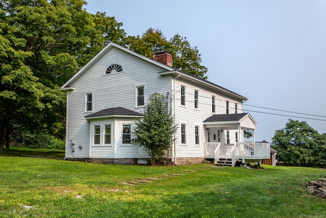 back of property featuring a deck and a yard