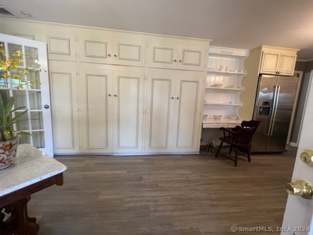 interior space featuring dark wood-type flooring, white cabinets, and stainless steel refrigerator with ice dispenser