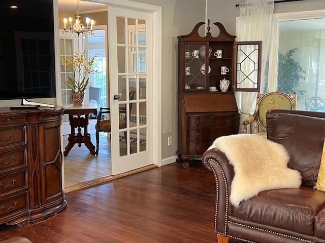 living area with dark hardwood / wood-style flooring, a notable chandelier, and ornamental molding