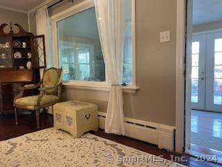 living area with dark wood-type flooring, a baseboard heating unit, and plenty of natural light