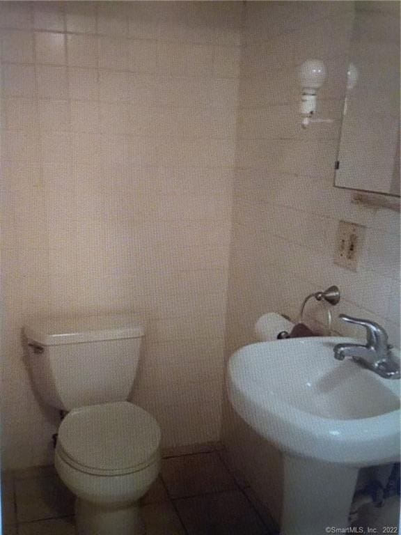 bathroom featuring toilet, a sink, and tile walls