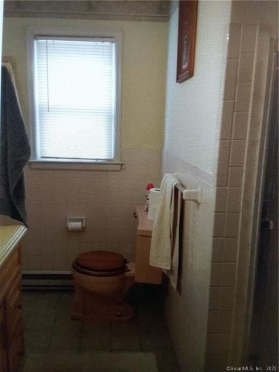 bathroom featuring tile patterned floors, toilet, vanity, a baseboard heating unit, and walk in shower