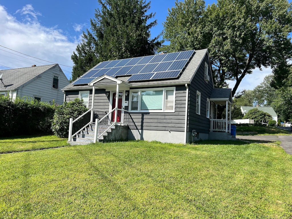 bungalow-style house with a front lawn and solar panels