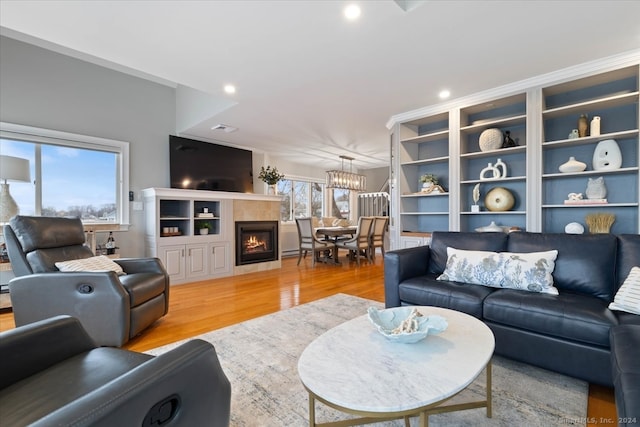 living room with an inviting chandelier, hardwood / wood-style floors, and a tiled fireplace