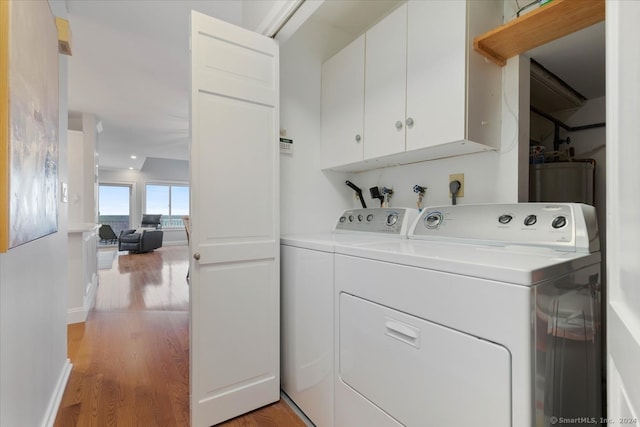 laundry room featuring cabinets, light hardwood / wood-style flooring, and washer and clothes dryer