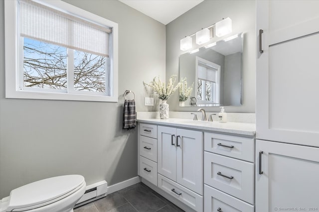 bathroom featuring toilet, a baseboard heating unit, vanity, and a wealth of natural light