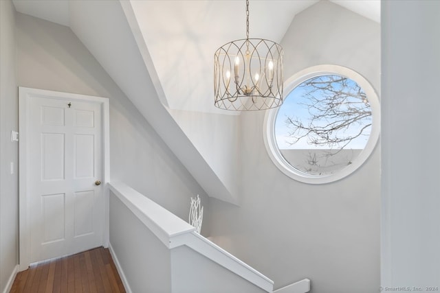 stairs with a notable chandelier, vaulted ceiling, and hardwood / wood-style floors