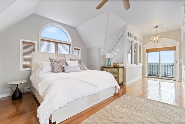 bedroom featuring vaulted ceiling, wood-type flooring, a baseboard radiator, and ceiling fan with notable chandelier