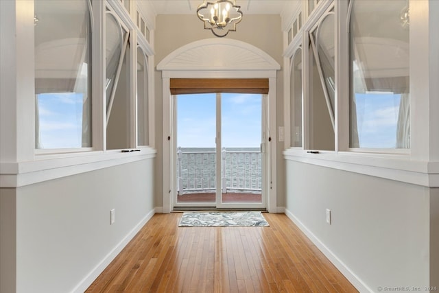 doorway to outside featuring light hardwood / wood-style floors and an inviting chandelier