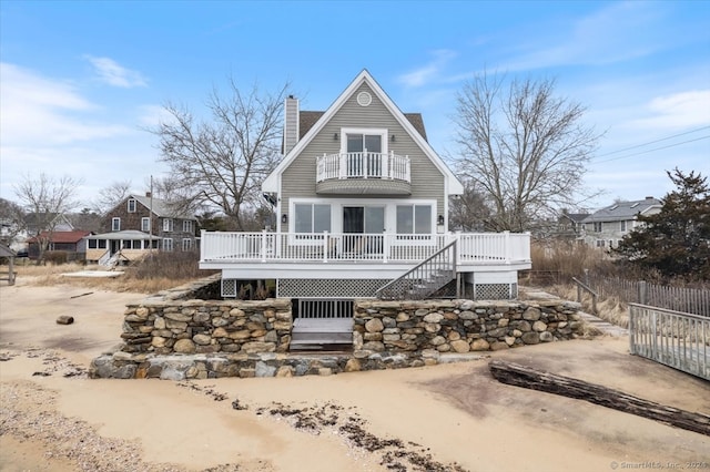 rear view of house featuring a wooden deck and a balcony