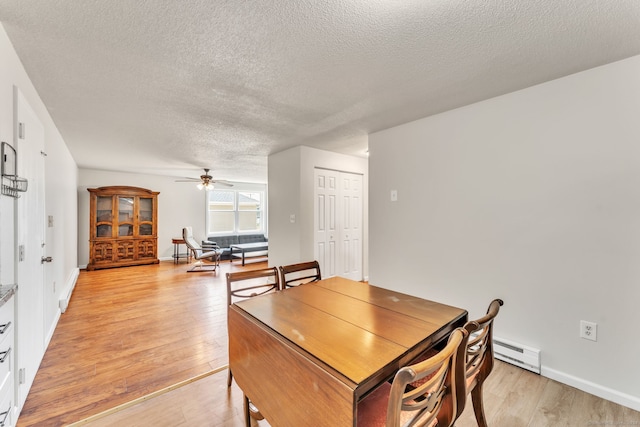 dining area featuring a textured ceiling, ceiling fan, a baseboard heating unit, and light wood-type flooring