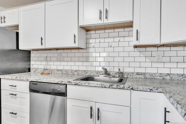 kitchen featuring stainless steel dishwasher, sink, tasteful backsplash, and white cabinets