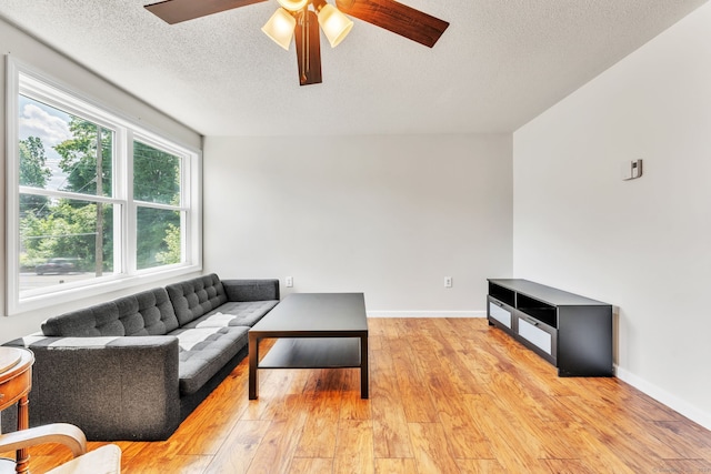 living room featuring ceiling fan, a textured ceiling, and light hardwood / wood-style floors