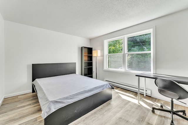 bedroom with a textured ceiling, baseboard heating, and light wood-type flooring