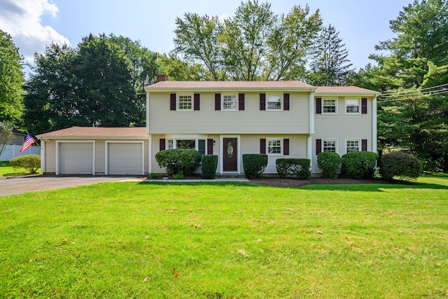 colonial-style house featuring a front yard and a garage