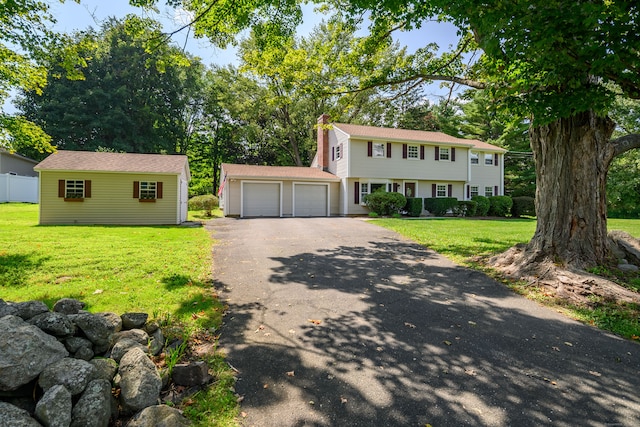 colonial inspired home featuring a front yard, a garage, and an outdoor structure