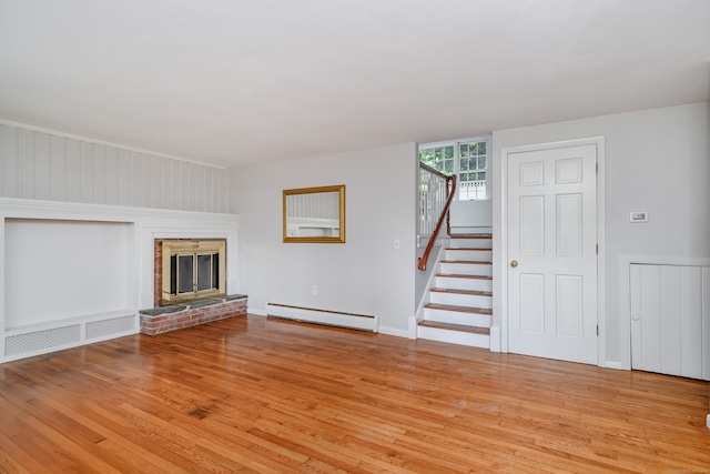 unfurnished living room with light wood-type flooring, a fireplace, and a baseboard heating unit