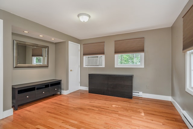 unfurnished living room featuring cooling unit, light hardwood / wood-style floors, and baseboard heating