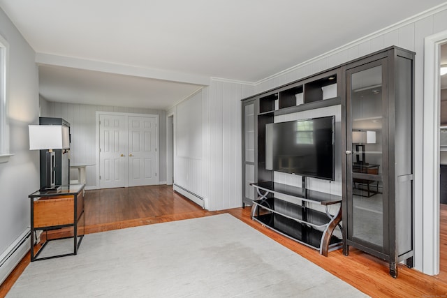 interior space with hardwood / wood-style flooring, a baseboard radiator, and ornamental molding