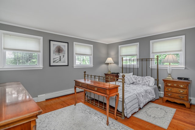 bedroom featuring ornamental molding, baseboard heating, and hardwood / wood-style flooring