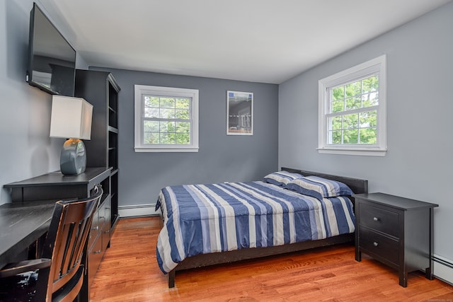 bedroom with light wood-type flooring and a baseboard heating unit