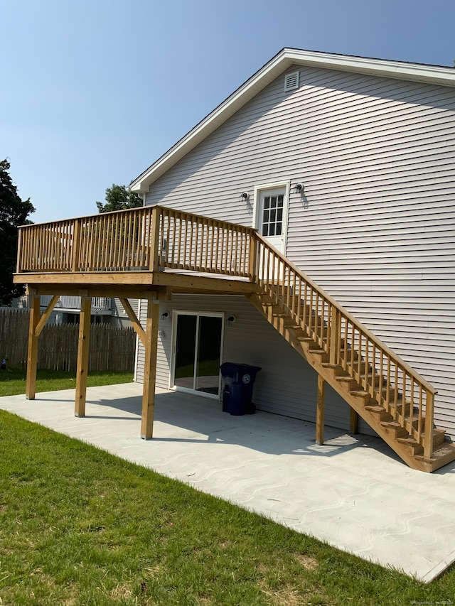 rear view of house featuring a deck, a patio area, and a lawn