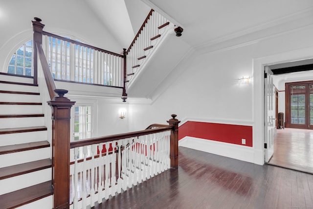 staircase featuring a towering ceiling, wood-type flooring, and plenty of natural light