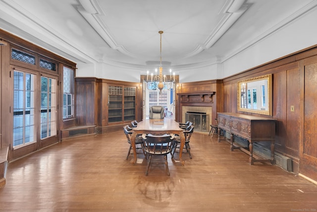 dining space with crown molding, an inviting chandelier, a tray ceiling, and hardwood / wood-style floors