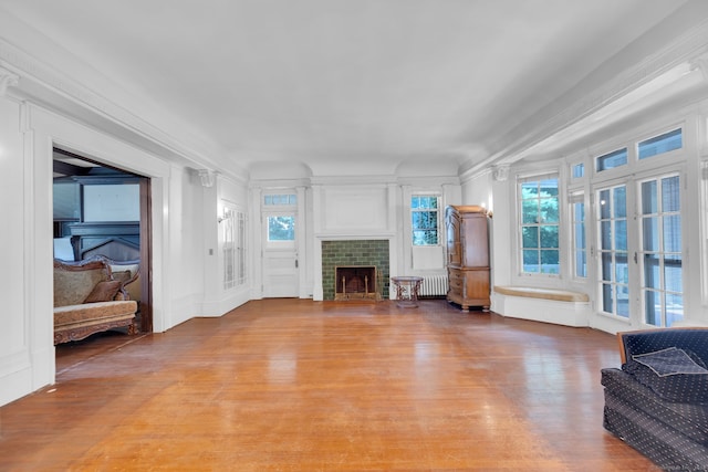 living room with radiator, light wood-type flooring, and a tile fireplace