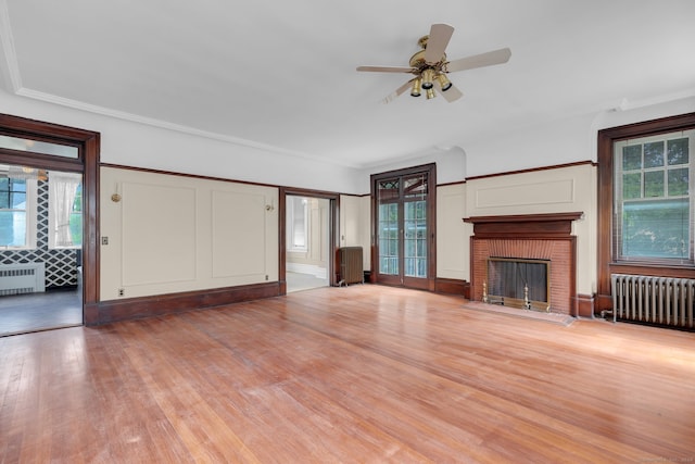 unfurnished living room with ceiling fan, a fireplace, light hardwood / wood-style floors, and radiator