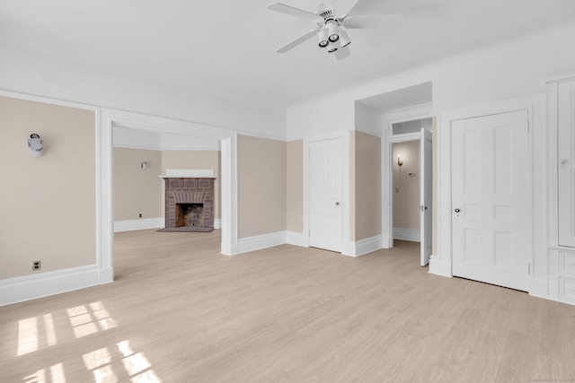 unfurnished living room featuring ceiling fan, light wood-type flooring, and a brick fireplace