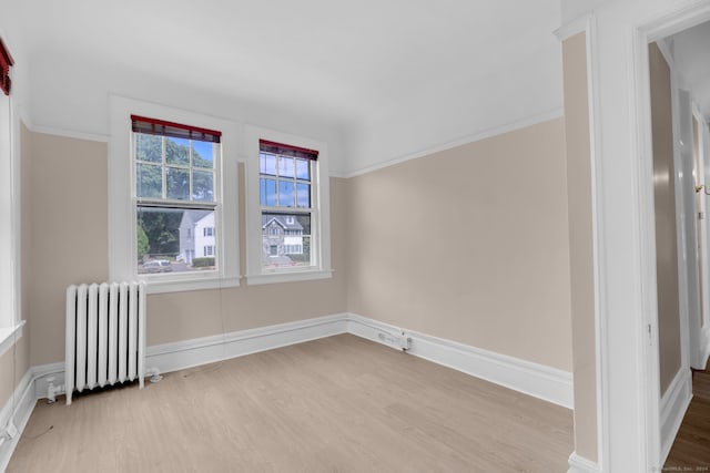 unfurnished room featuring light wood-type flooring, ornamental molding, and radiator