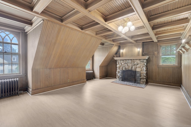 bonus room featuring a stone fireplace, light hardwood / wood-style flooring, radiator heating unit, wooden ceiling, and wooden walls